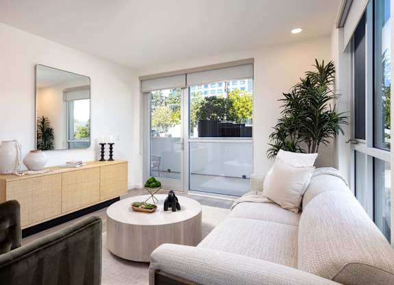 Living room with neutral sofa and sliding glass door at Elements Apartments, Irvine, CA