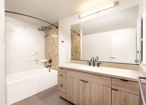 Bathroom with tub shower combo and wood floating vanity at Elements Apartments, Irvine