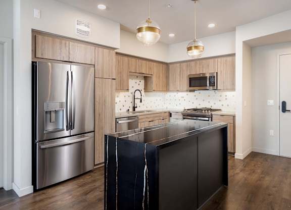 Contemporary kitchen with stainless appliances and black island at Elements Apartments, Irvine, CA 92612