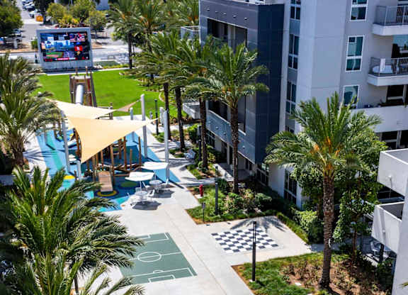Aerial view of courtyard with basketball court and palm trees at Elements Apartments, California