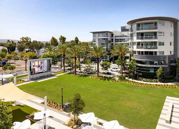 Outdoor lawn with palm trees and modern building at Elements Apartments, Irvine, CA 92612