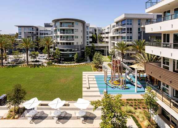 Courtyard with playground lawn and white shade structures at Elements Apartments, Irvine, CA