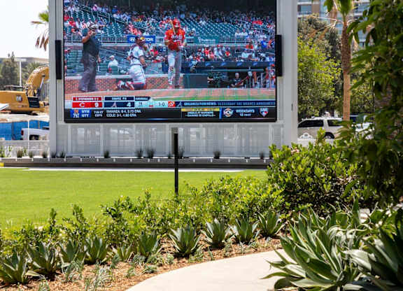 Large outdoor video screen by landscaped lawn and walkway at Elements Apartments, Irvine