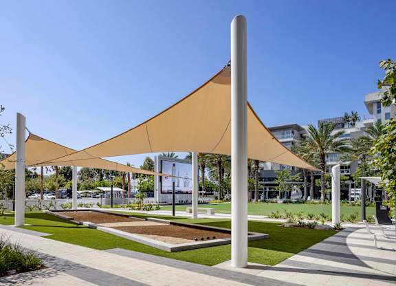 Outdoor recreation lawn with shade canopies and bocce courts at Elements Apartments, Irvine, California