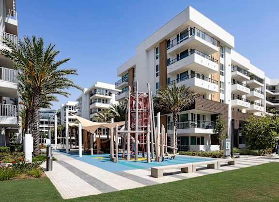 Playground with climbing structure and blue safety surfacing at Elements Apartments, Irvine