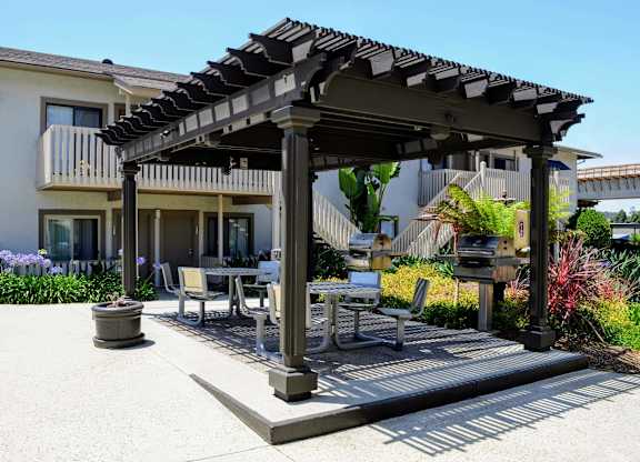 A patio with a table and chairs under a pergola.at La Jolla Canyon Apartments, San Diego