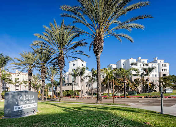 Monument sign with palm trees and white buildings at La Jolla Crossroads Apartments, San Diego, 92122
