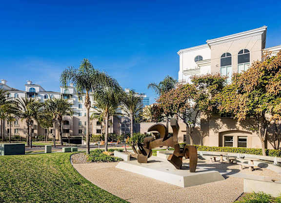 Outdoor courtyard with modern sculpture and palm trees at La Jolla Crossroads Apartments, San Diego