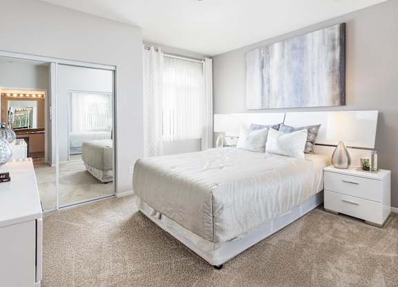 Spacious bedroom with mirrored closet doors and carpet at La Jolla Crossroads Apartments, San Diego, CA