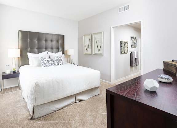 Bedroom with tufted headboard and ensuite bathroom at La Jolla Crossroads Apartments, San Diego, California