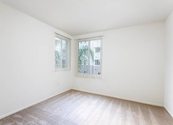 Empty bedroom with carpet and two windows at La Jolla Crossroads Apartments, San Diego