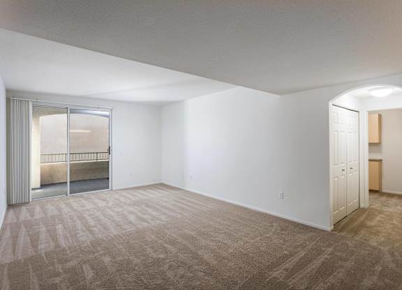 Empty living room with balcony access and carpet at La Jolla Crossroads Apartments, San Diego, CA