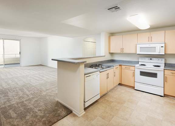 Open kitchen with breakfast bar and carpeted living space at La Jolla Crossroads Apartments, San Diego, 92122