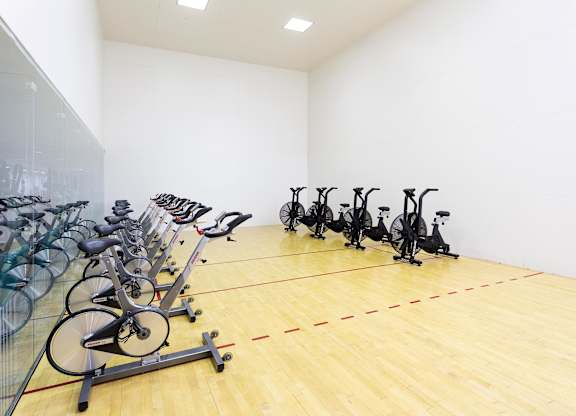 Indoor cycling studio with spin bikes and racquetball court at La Jolla Crossroads Apartments, San Diego