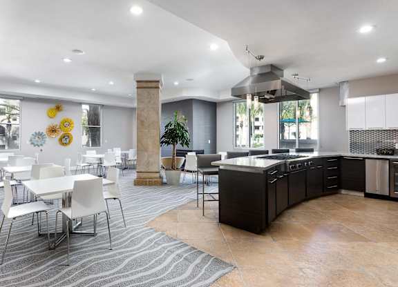 Community clubhouse with kitchen island and dining tables at La Jolla Crossroads Apartments, California, 92122