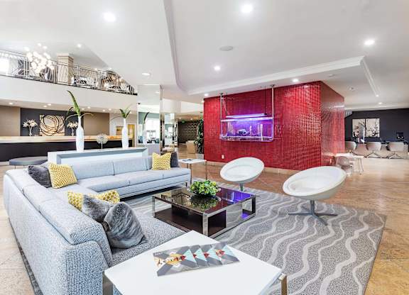 Lobby with gray sectional sofa and red tile feature wall at La Jolla Crossroads Apartments, San Diego, CA 92122