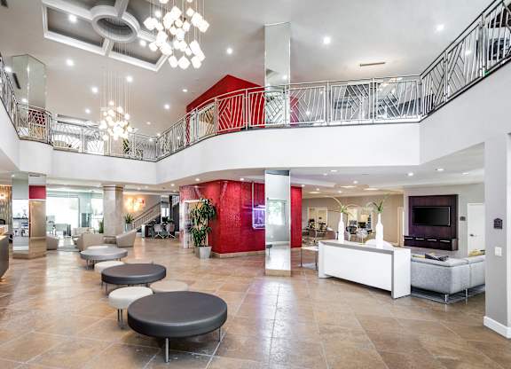 Grand two story lobby with decorative railings and red accent walls at La Jolla Crossroads Apartments, San Diego, California