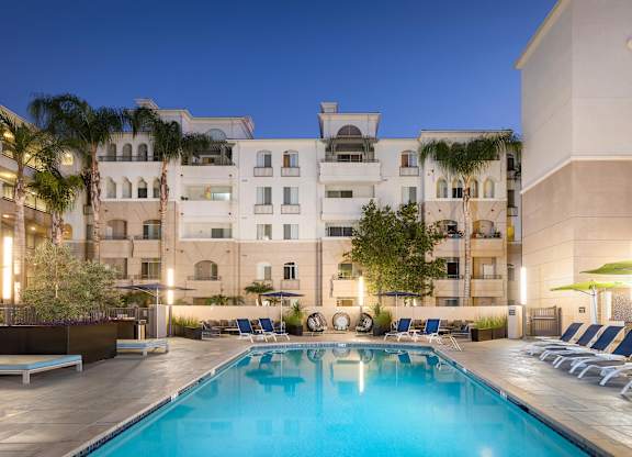 Evening pool deck with lounge chairs and palm trees at La Jolla Crossroads Apartments, San Diego, CA 92122