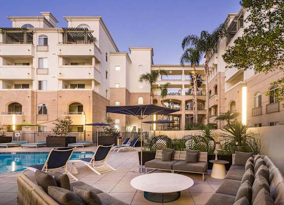 Poolside lounge area with outdoor furniture and umbrellas at La Jolla Crossroads Apartments, San Diego, 92122