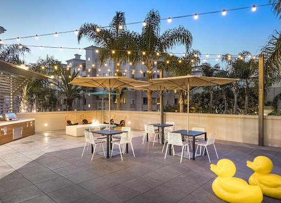 Rooftop patio with dining tables and umbrellas at La Jolla Crossroads Apartments, San Diego, California