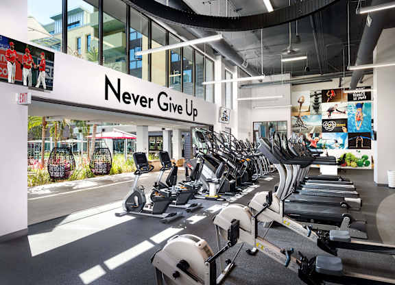 Fitness center with motivational signage and exercise machines at Metropolis Apartments, IRVINE, California