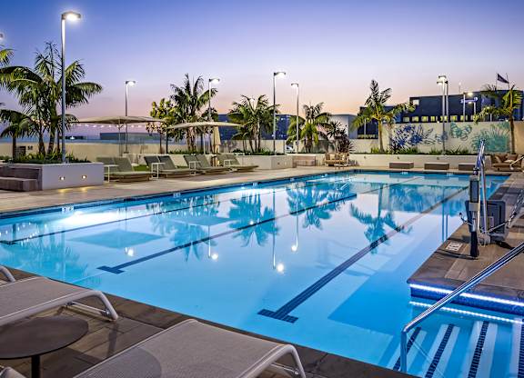 Resort style lap pool with lounge chairs at dusk at Elements Apartments, Irvine, CA
