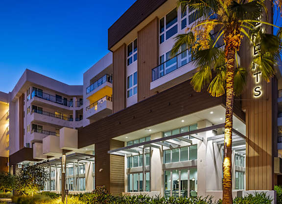 Modern building entrance with illuminated palm tree at Elements Apartments, Irvine, CA