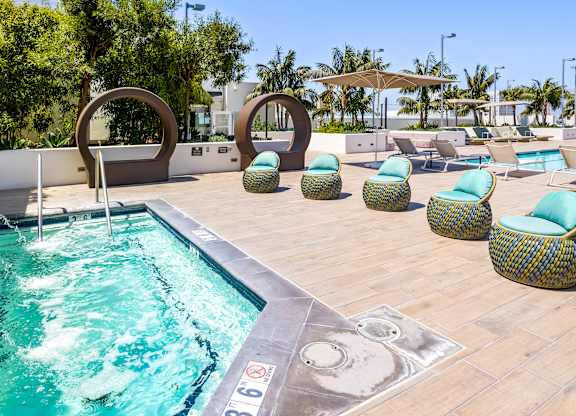 Spa with decorative sculptures and woven lounge chairs at Elements Apartments, Irvine