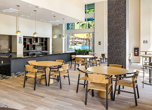 Community kitchen with dining tables and pendant lighting at Elements Apartments, Irvine
