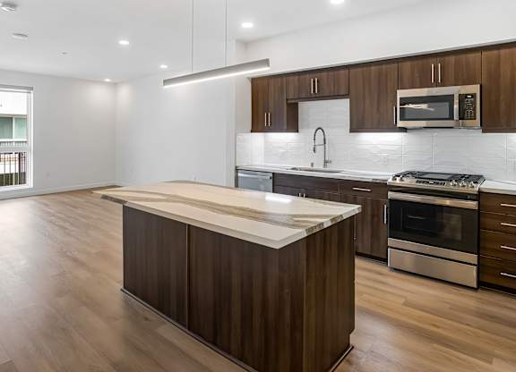 Modern kitchen with island and wood cabinetry at Elements Apartments, California, 92612