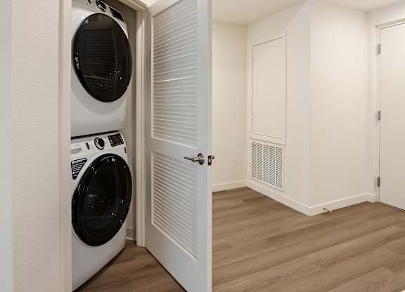 Stacked washer and dryer with louvered closet door at Elements Apartments, California