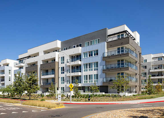 Exterior of apartment building with a roundabout and crosswalk in the front.