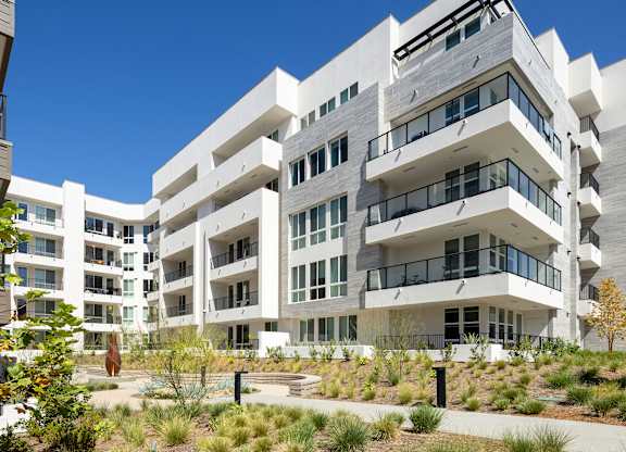 Exterior of apartment building with landscaped walkway.