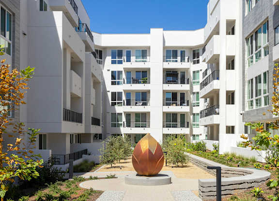 Exterior of apartment complex with a large golden egg sculpture in front.