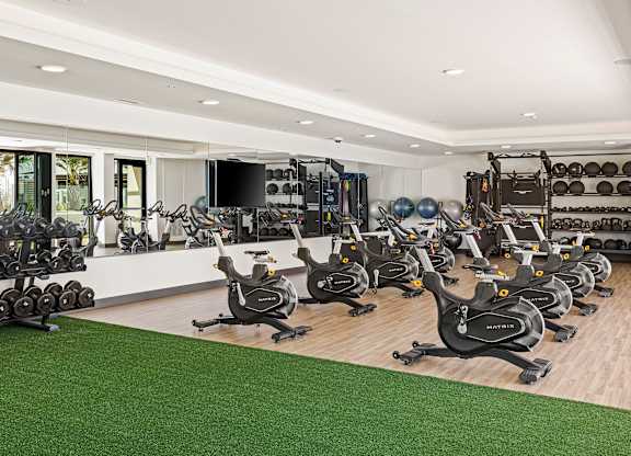 A gym with a variety of exercise equipment including stationary bikes and dumbbells.