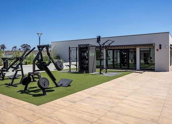 An outdoor gym with a variety of equipment including weights and a bench.