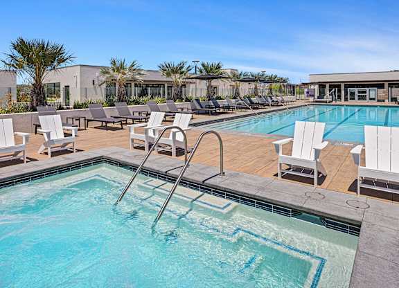 A spacious jacuzzi overlooking a community pool and palm trees.