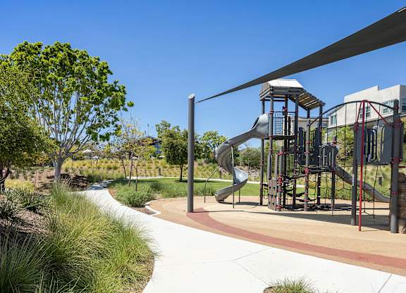 A playground with a slide and a tree.