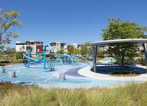 A playground with a blue swing set and a roundabout.