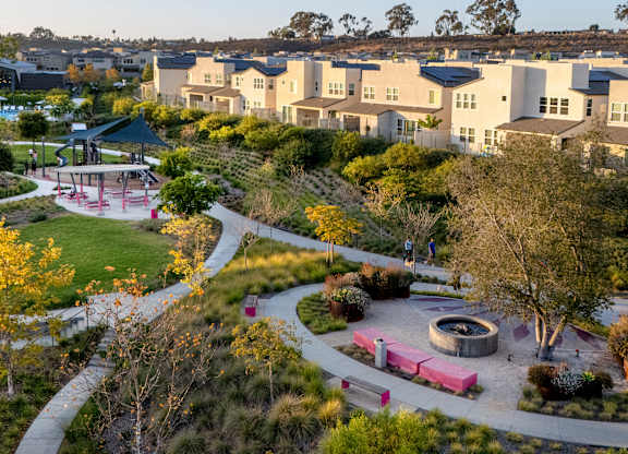 A park area with a circular structure in the middle and a playground to the left.
