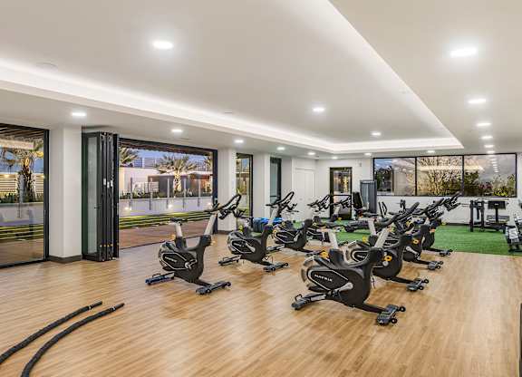 A gym with rows of stationary bikes and additional equipment in the back.