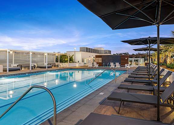 A community pool with sun loungers and umbrellas.