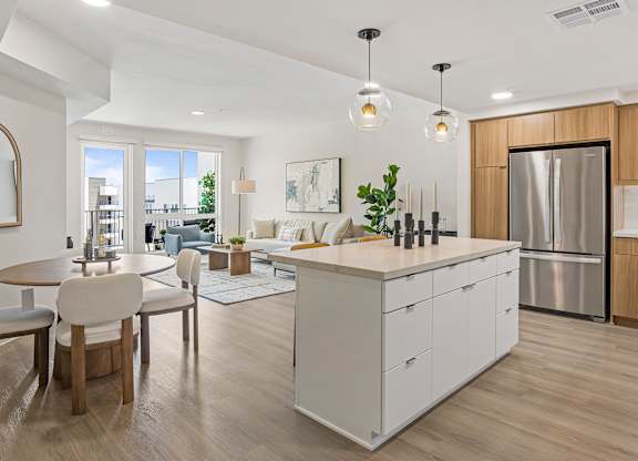 A bright open-concept kitchen with an island overlooking a dining area and living room.