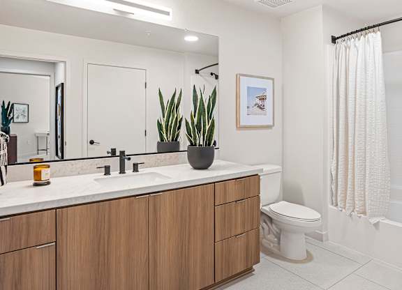 A modern bathroom with a white sink and wooden cabinets.