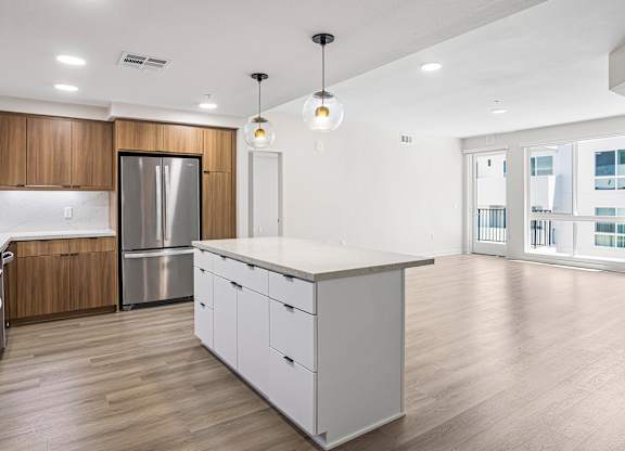 A modern kitchen with a large island and wooden cabinets.