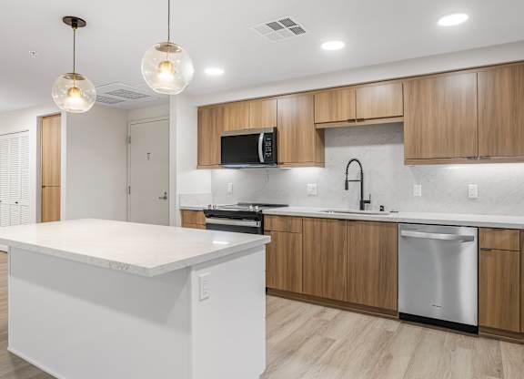 A modern kitchen with wooden cabinets and a white island.