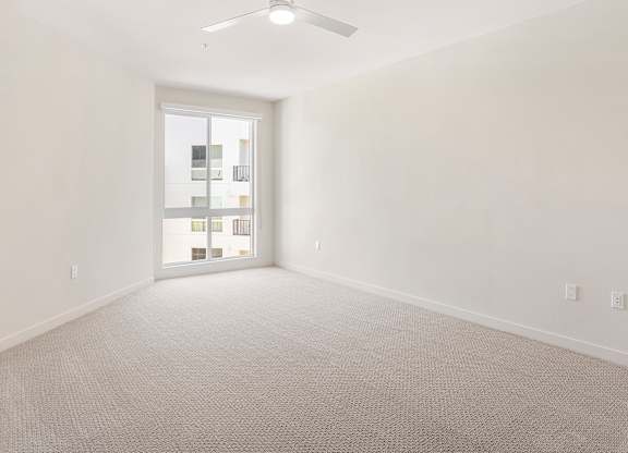 A room with a carpeted floor and a ceiling fan.