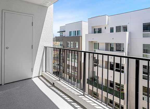 A white door is on the left of a balcony with a black railing.