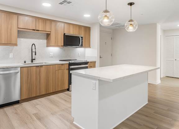 A modern kitchen with wooden cabinets and a white island.
