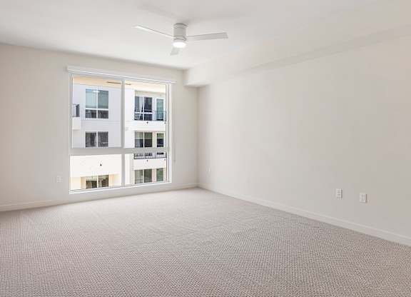 A room with a ceiling fan and a large window.